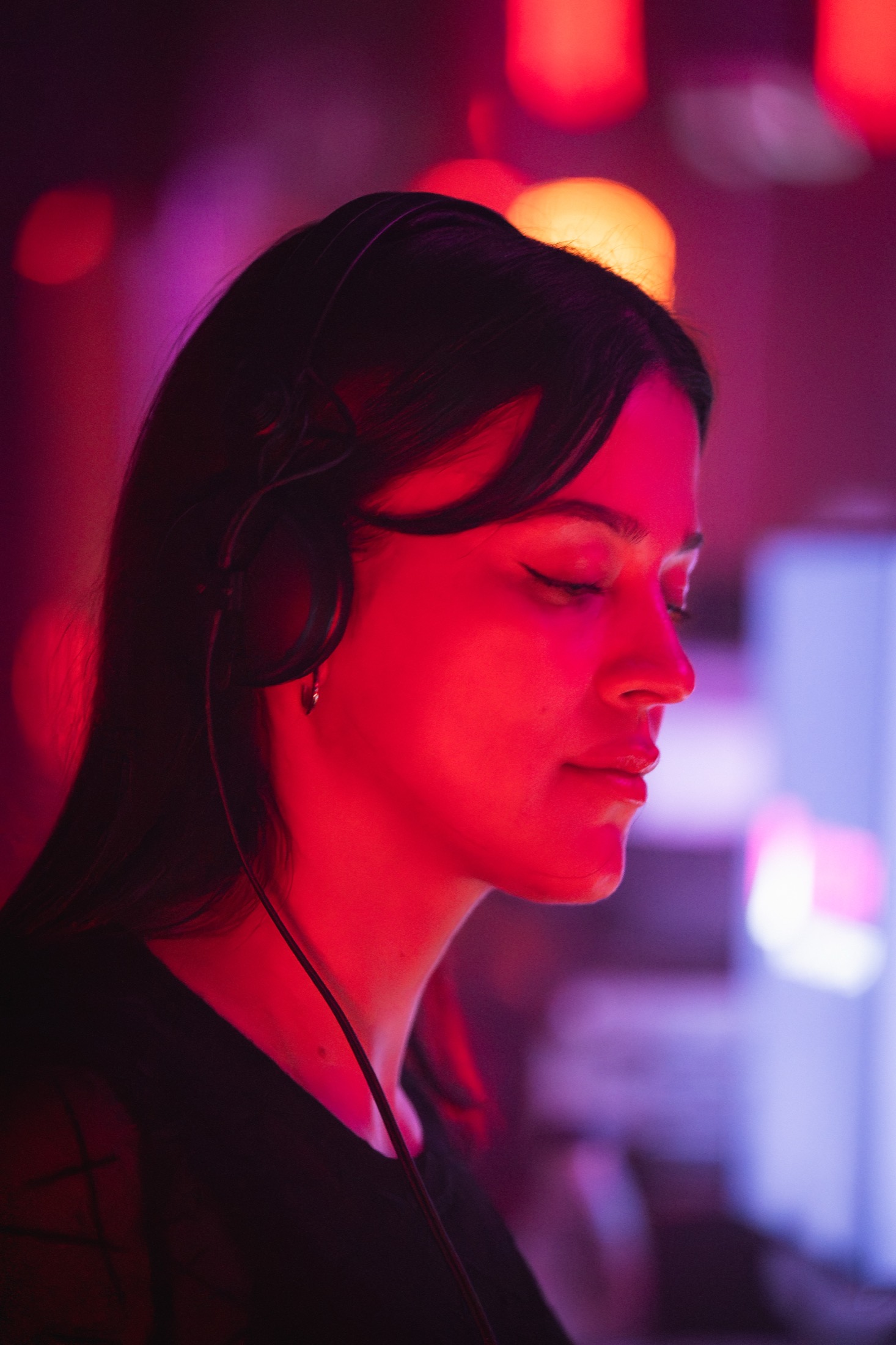 DJ de perfil con audífonos y ojos cerrados bajo luz roja — Libraphotos